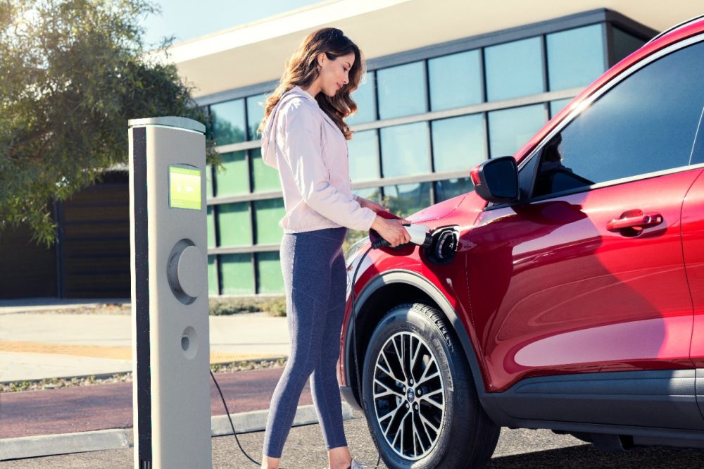 Woman charging a Ford Escape Plug-In Hybrid at a public charging station | Ford May 2021 sales results