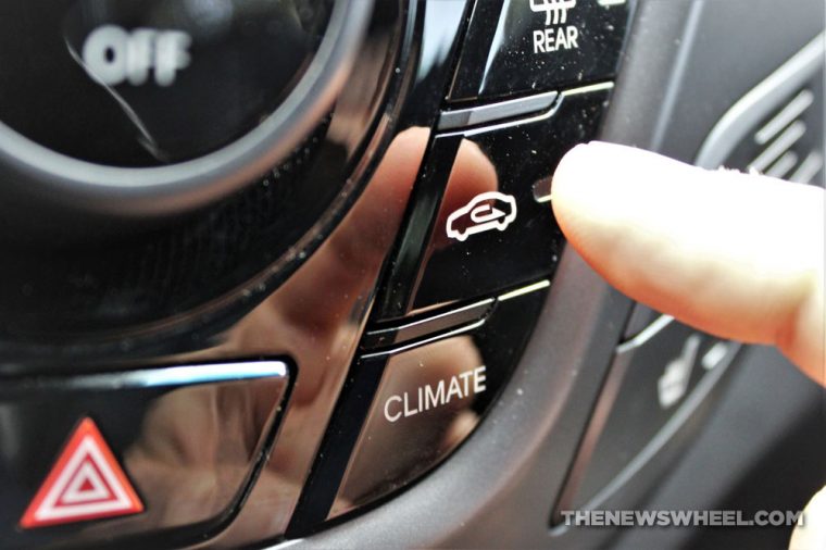 A finger pressing the recirculation button in a car