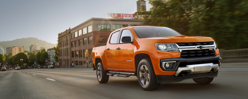 2021 Chevrolet Colorado driving in a city with mountains in the background