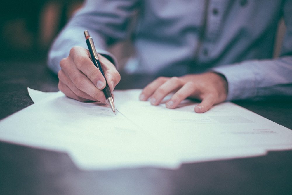 Man writing on paper to symbolize F1 teams signing new Concorde Agreement