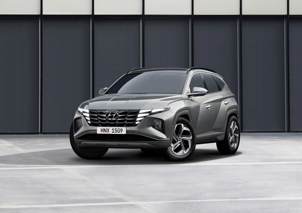 Front side view of silver 2022 Hyundai Tucson parked in front of dark gray wall