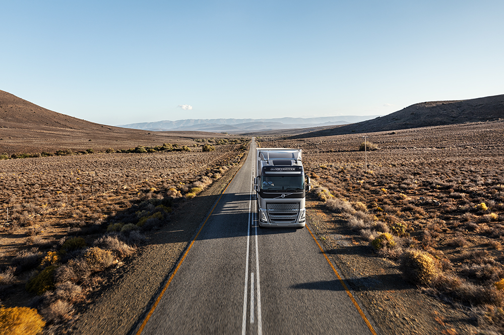 Professional truck driver in Volvo Truck on desert road