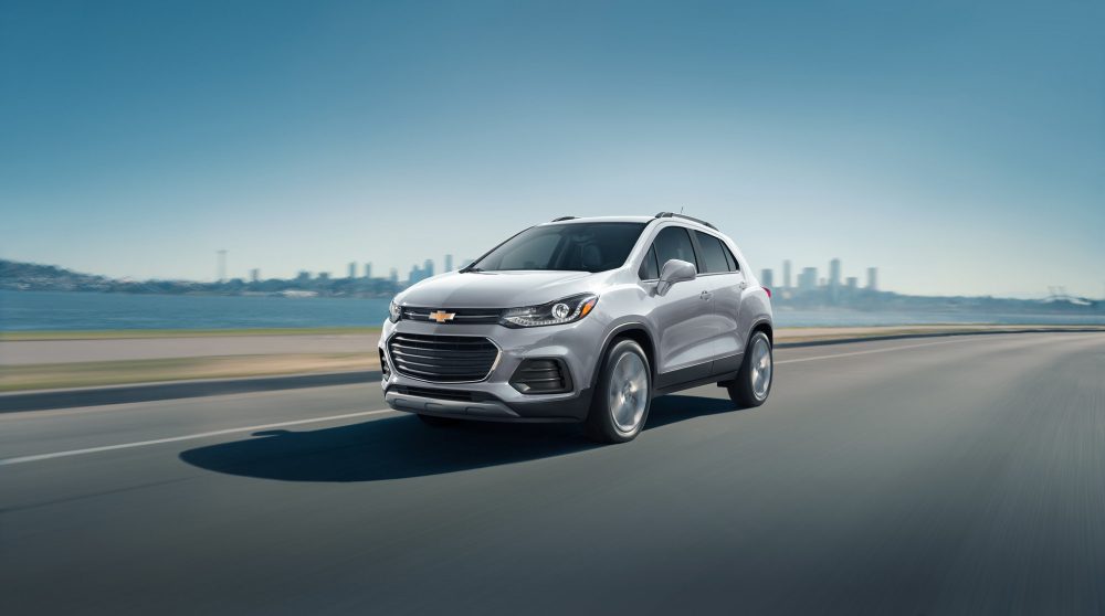 The 2021 Chevrolet Trax LT driving on the road with a city in the background