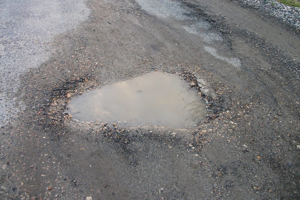 Pothole in road with water puddle