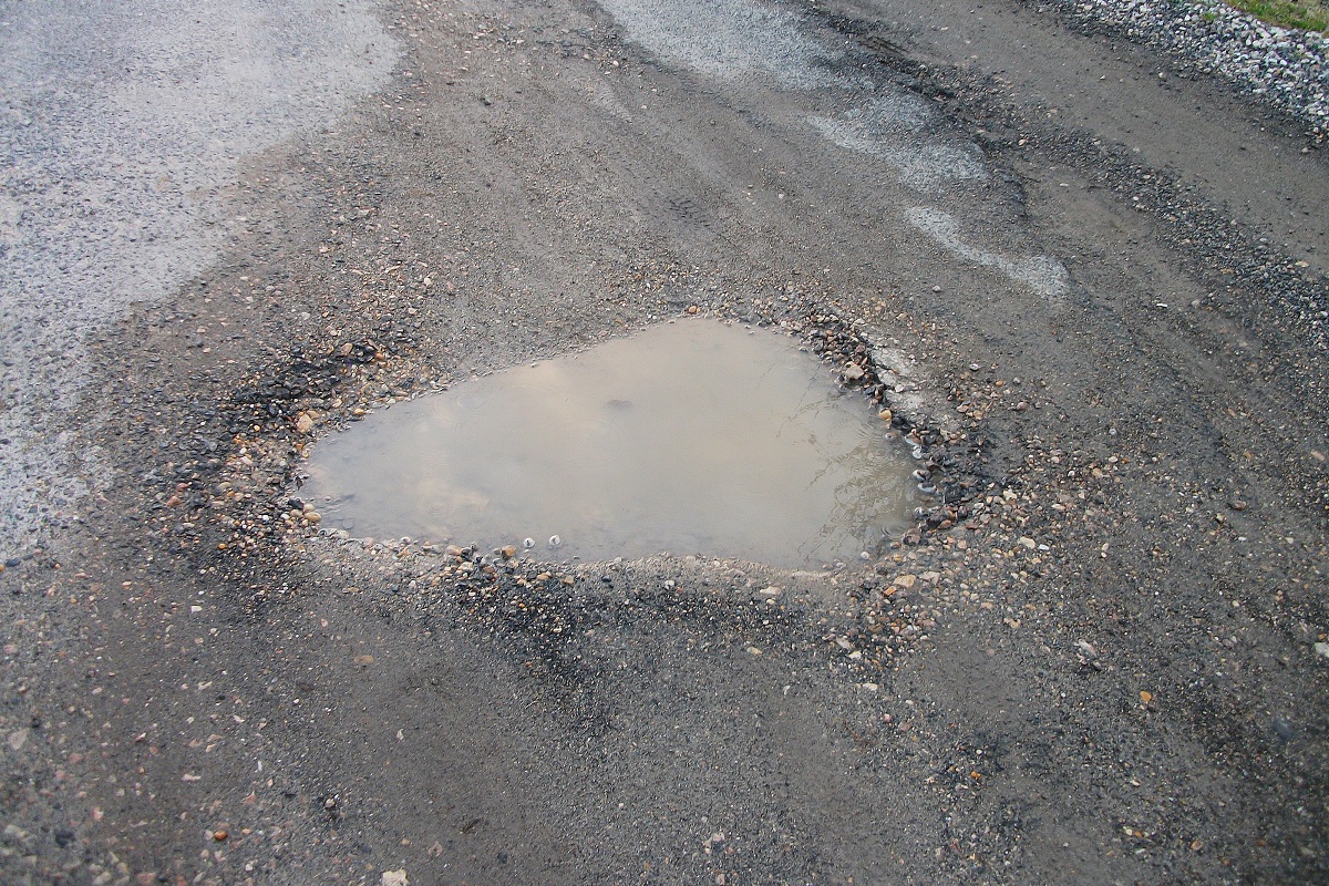 Pothole in road with water puddle