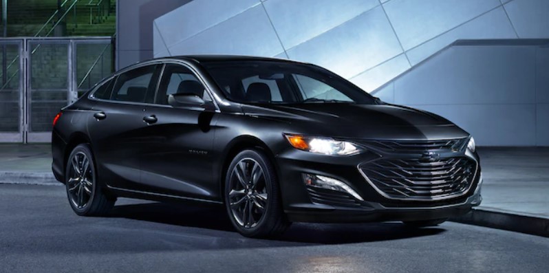 Black 2021 Chevrolet Malibu parked in front of a modern building