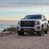 2021 GMC Yukon AT4 SUV parked on the edge of a sandy cliff overlooking a body of water