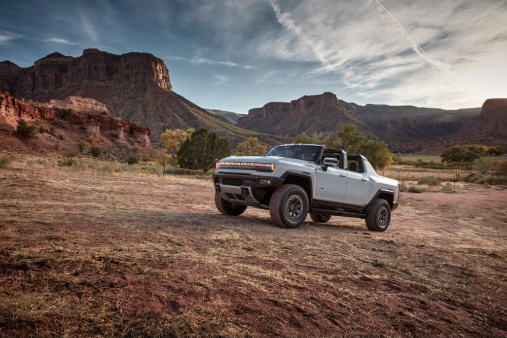 Front side view of 2022 GMC Hummer EV off-road with rock formations and mountains in background