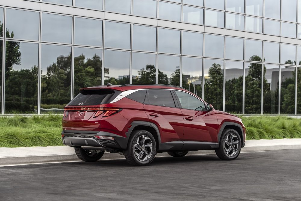 Rear side view of 2022 Hyundai Tucson parked in front of reflective windows