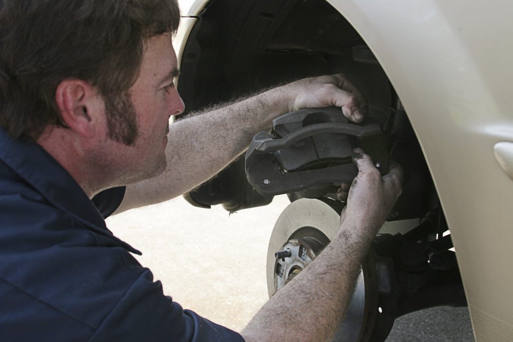 A man changing brake pads on a car