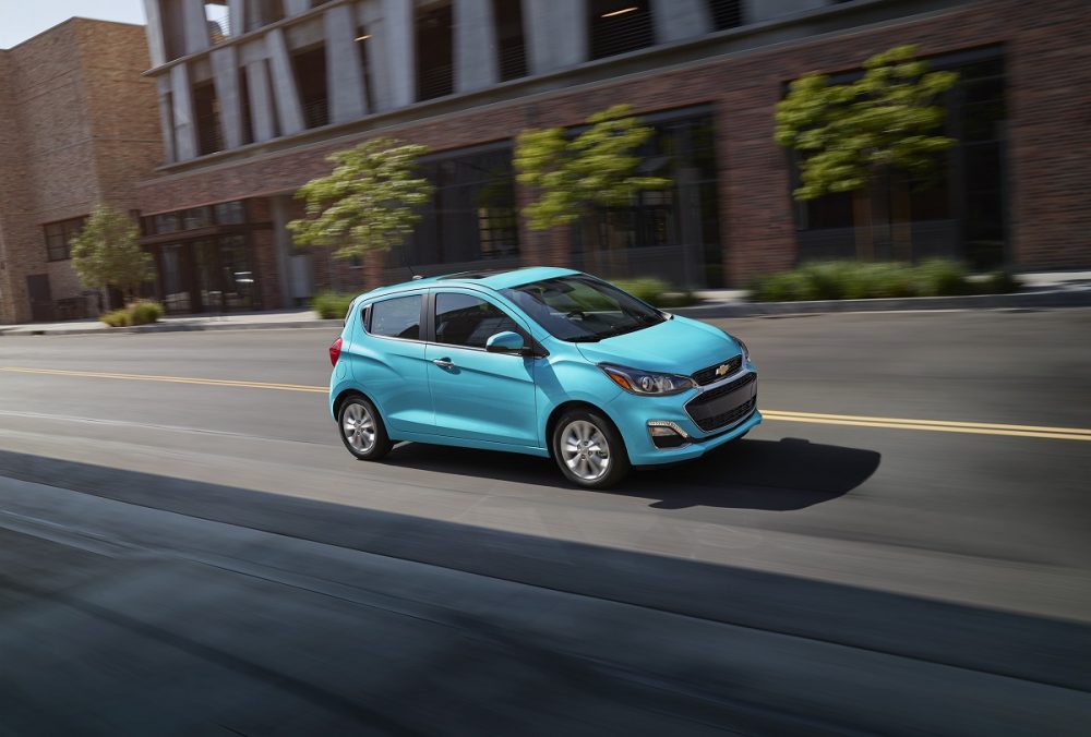 Front side view of blue 2021 Chevrolet Spark driving down road