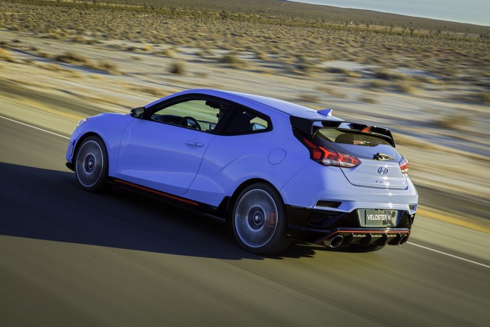 Rear side view of Hyundai Veloster N driving down road at high speed