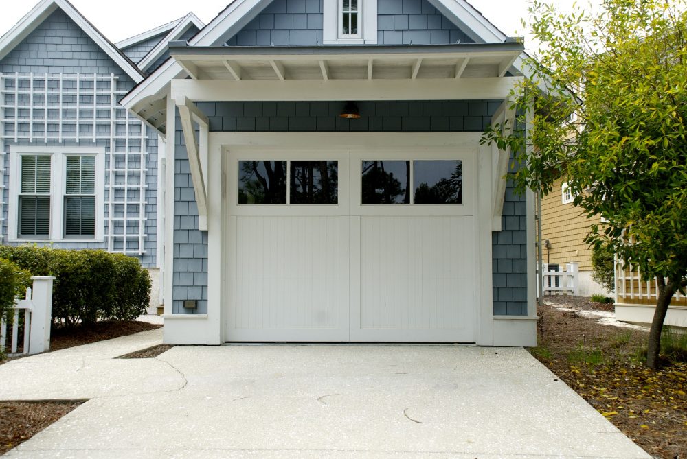 White wooden garage door with square windows in the top, on an attached garage