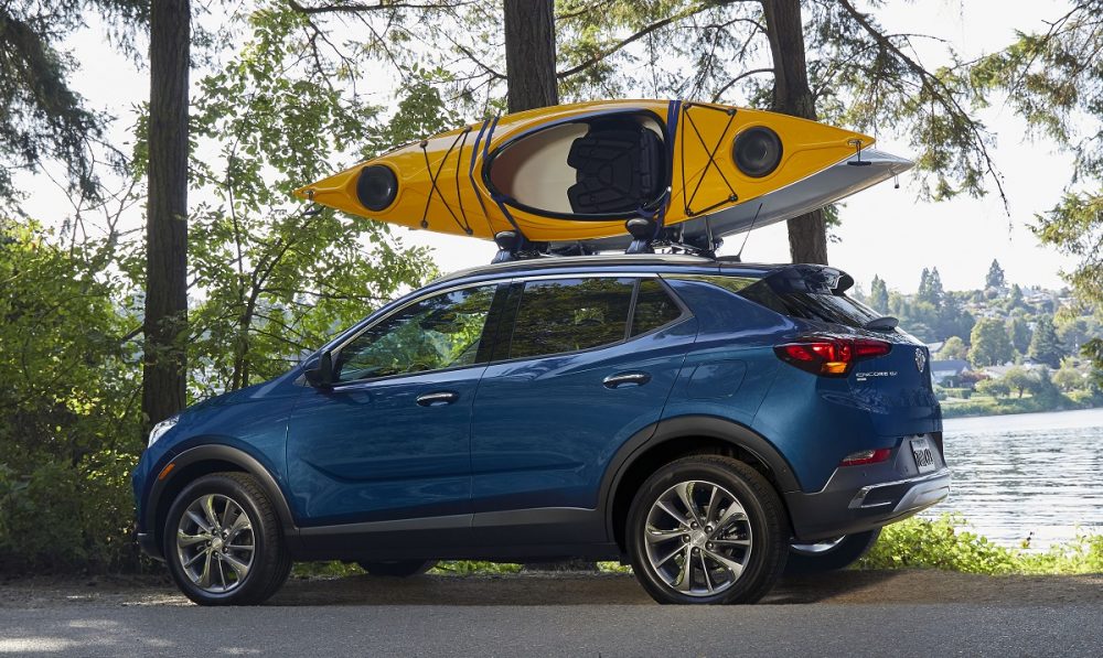 2021 Buick Encore GX with a kayak on the roof rack, parked by a lake or river.