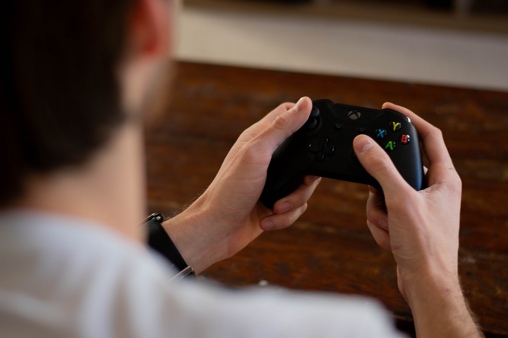 A man holding an Xbox controller, which you could ostensibly use to play my new breed of driving simulator.