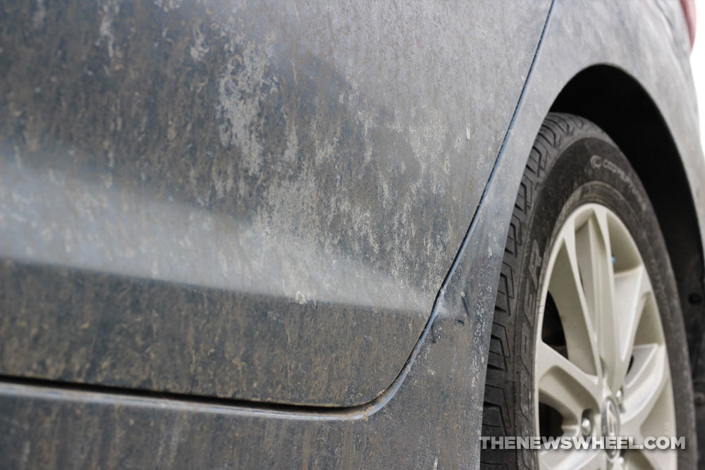 Lower panel of a car covered in dirt and road salt grime. 