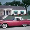 A promotional photo of a couple looking at a red 1957 Ford Thunderbird