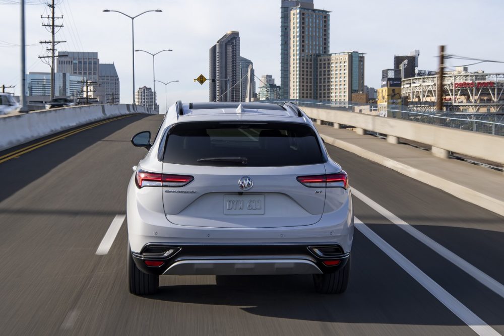 A rear view of a 2021 Buick Envision driving down a city street