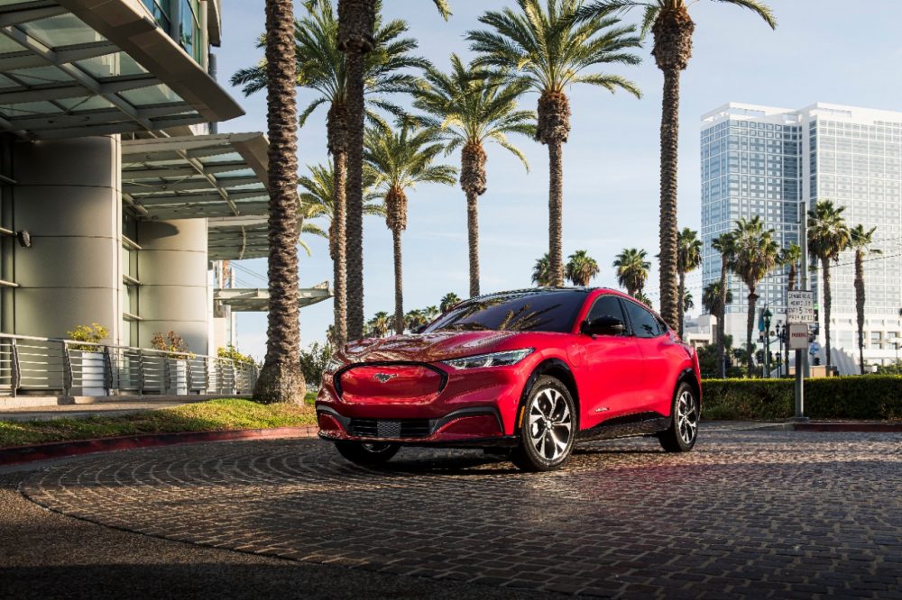 2021 Ford Mustang Mach-E parked in a city with tall buildings and palm trees in the background