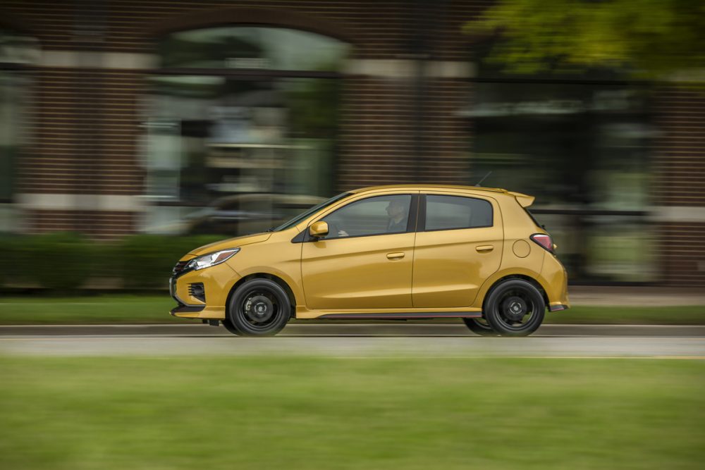 The 2021 Mitsubishi Mirage driving in front of a brick building