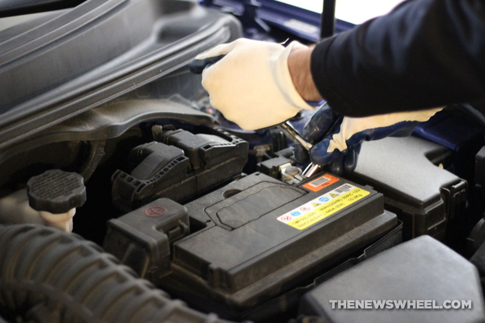 Changing a dead car battery by loosening terminal bolt with a wrench