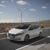 White Nissan Leaf driving on highway with windmills in the background