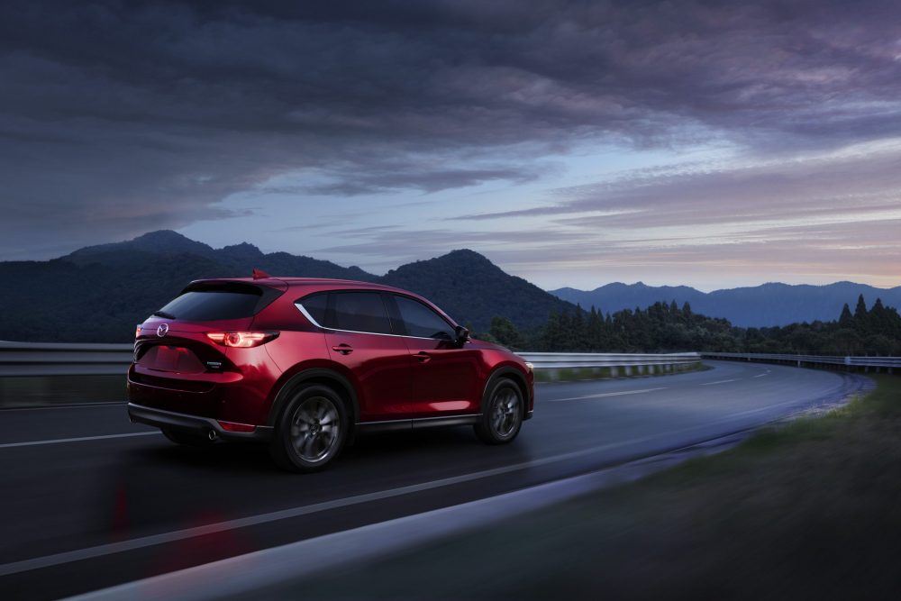 Red 2021 Mazda CX-5 cruising down the highway in the evening