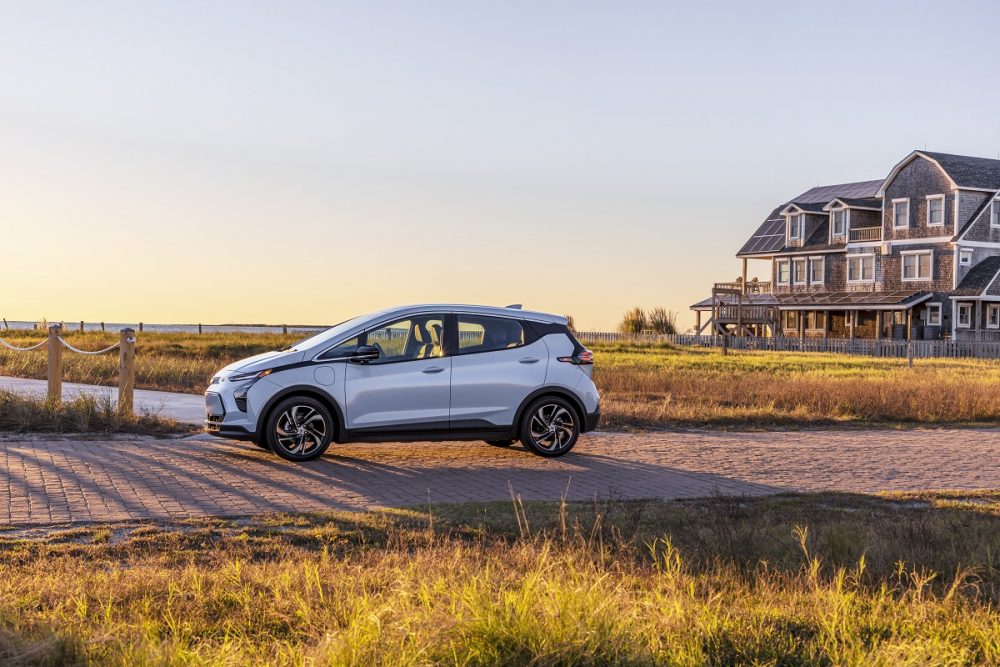 A side view of 2022 Chevrolet Bolt EV near a house