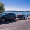 Front side view of Buick Enclave Avenir pulling boat trailer near water