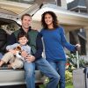 Family Road Trip picture of two adults, one male, one female, and a little boy sitting on the back of their vehicle