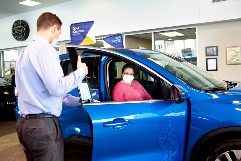 Customer and dealer salesperson go over a Ford Blue Advantage Gold Certified vehicle