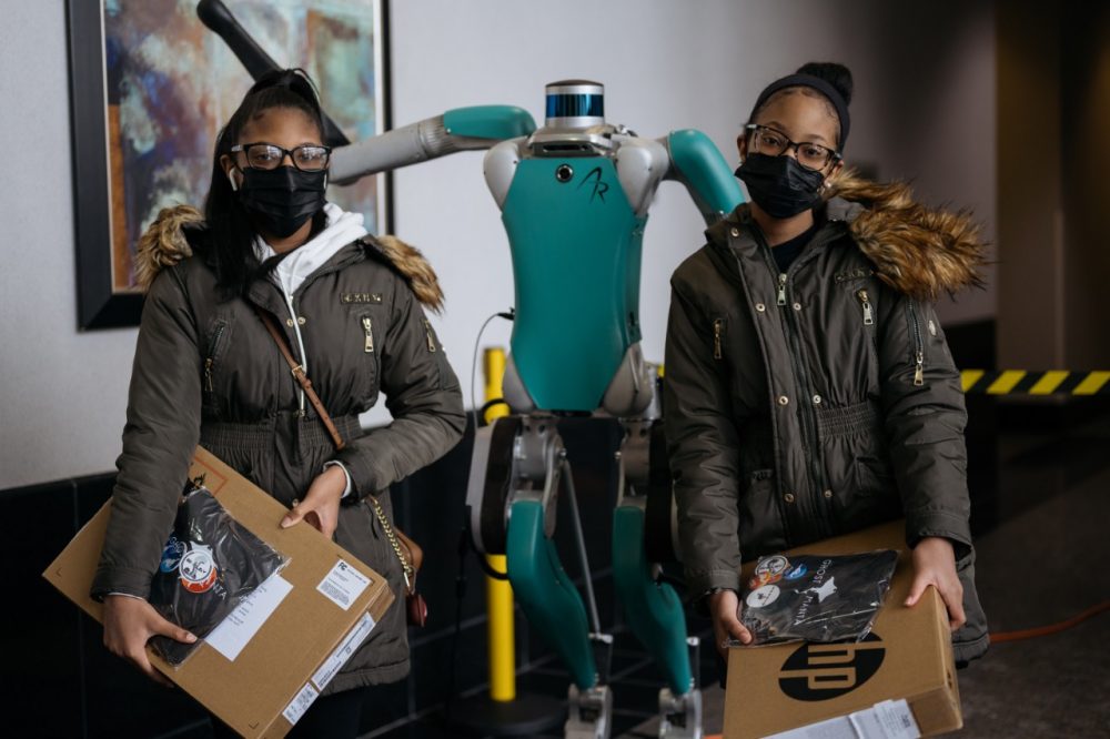 Two students pose for a photo with the Digit delivery robot