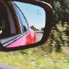 A rear view mirror on a red sedan