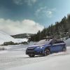 A blue 2021 Subaru Crosstrek driving through the snowy terrain with trees behind it