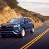 A blue 2021 Volkswagen Atlas driving down a road at sunset