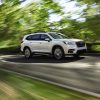 A white 2021 Subaru Ascent speeding down a scenic road with motion-blur