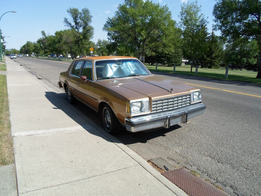 A brown Buick Century parked along the side of the road. A similar vehicle can be seen in "Fargo."