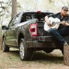 Luke Combs sits in the bed of a 2021 Ford F-150 playing a guitar powered by an amp powered through the truck's Pro Power Onboard built-in gneerator