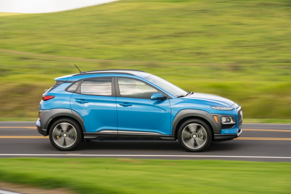 Side view of blue 2020 Hyundai Kona driving down road