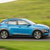 Side view of blue 2020 Hyundai Kona driving down road