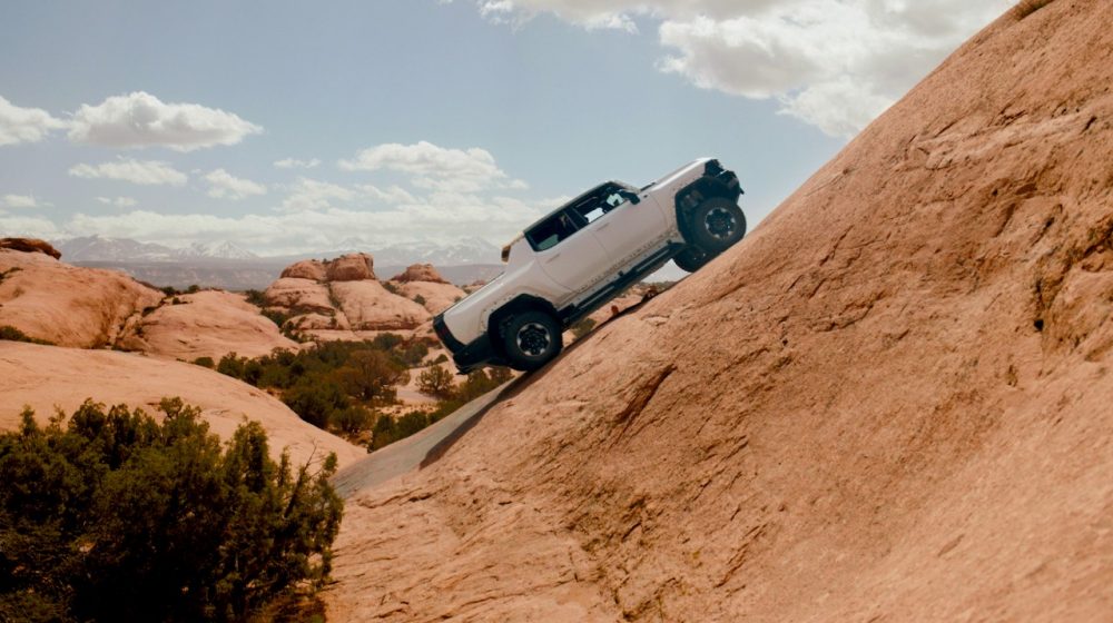 The GMC HUMMER EV Pickup driving up a sandy hill as part of testing