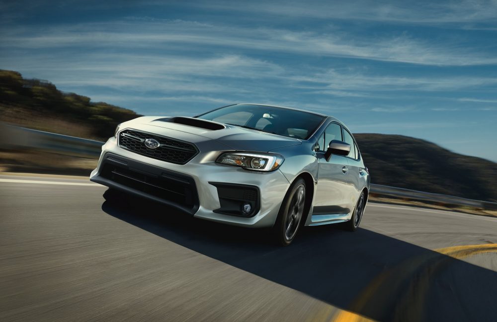 A Silver Subaru WRX rounding a corner and what is surely a high speed.