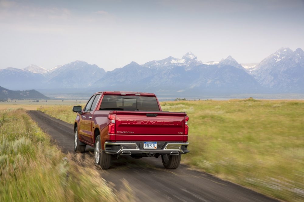 Rear view of 2020 Chevrolet Silverado 1500 LTZ driving down dirt road with mountains in background