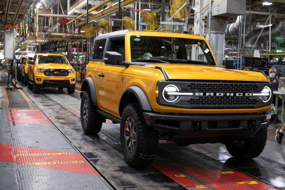 A Cyber Orange Ford Bronco two-door on the MAP assembly line in front of a nearly finished Ford Ranger