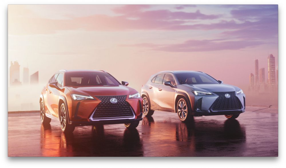 Red and silver 2021 Lexus UX models parked side by side in front of a sunset