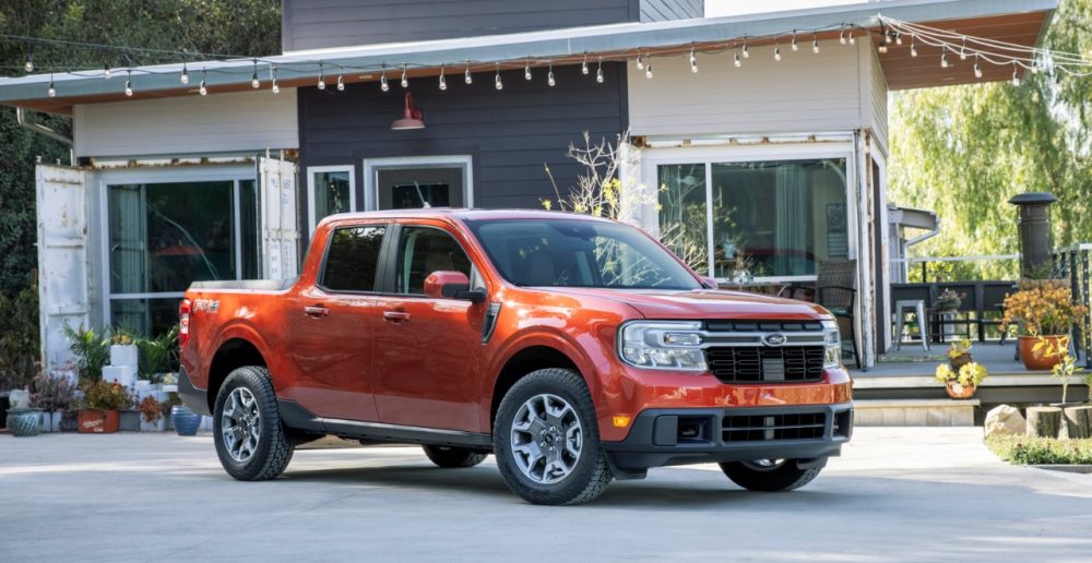 2022 Ford Maverick Lariat with 2.0-liter EcoBoost AWD in Hot Pepper Red in front of a cozy house with plenty of potted plants