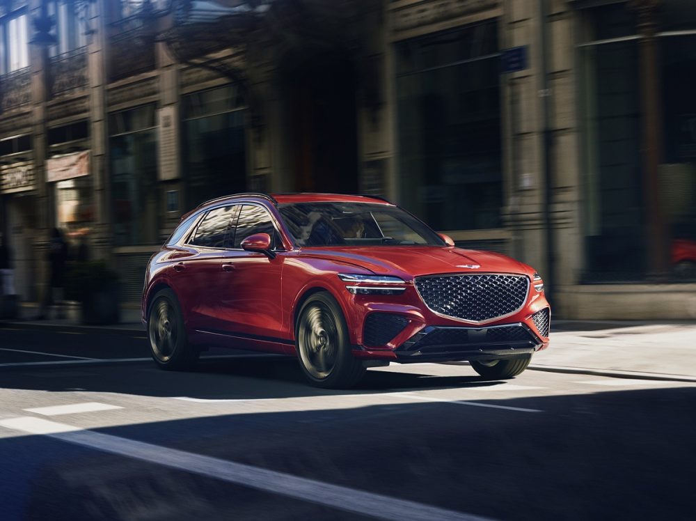 Front side view of 2022 Genesis GV70 driving in shadows on street