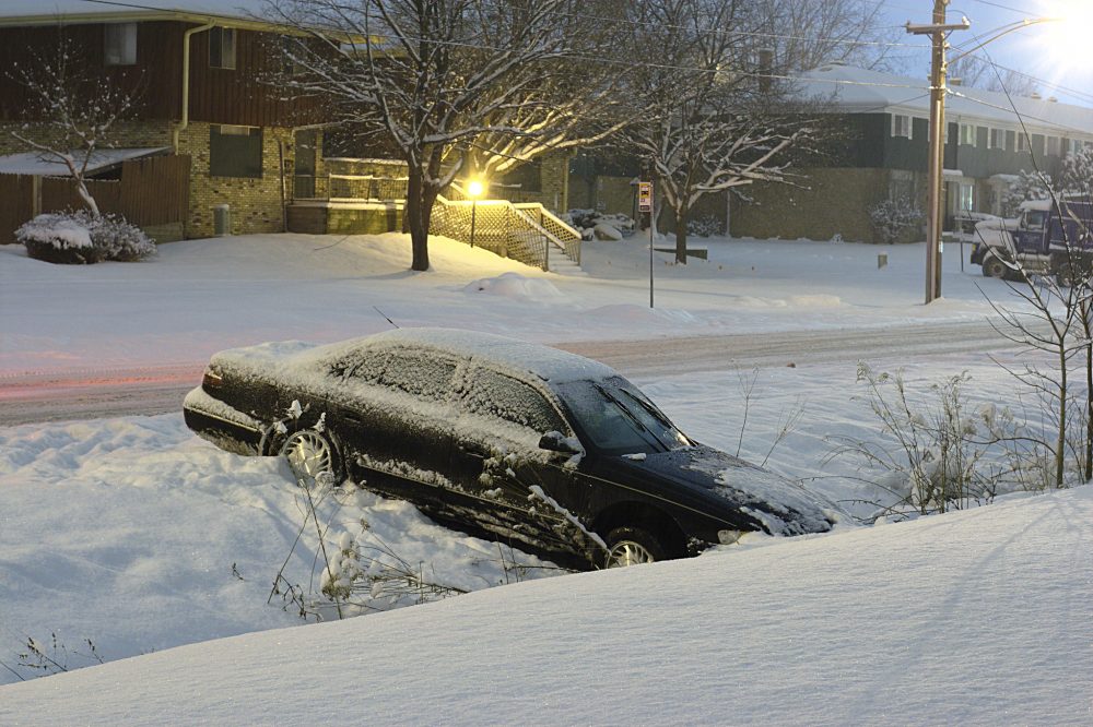 Black sedan stuck in a snowy ditch