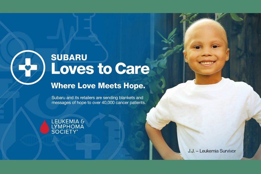 Leukemia survivor JJ proudly standing next to Subaru Loves to Care logo