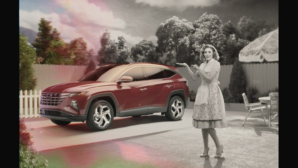 Ad still: black-and-white Wanda Maximoff stands next to red 2022 Hyundai Tucson